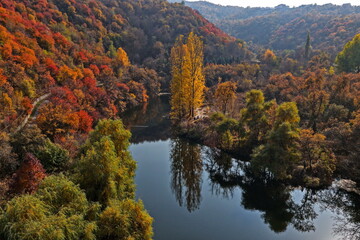 Soldier Lake. An urban lake surrounded by mountains with different vegetation. Autumn time, view from the drone.