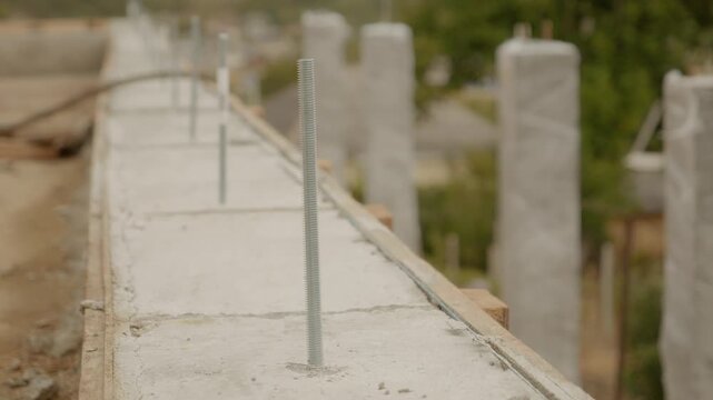 Wooden formwork is holding freshly poured concrete columns as they dry. This essential phase in house construction ensures structural stability and strength.