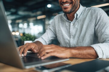 Confident middle-aged man smiling while working on a laptop in a bright modern office environment, suggesting productivity and success.