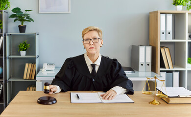 Woman judge signs legal document in courtroom. Symbol of justice and law, gavel on desk as official...