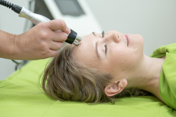 Naklejka premium Caucasian woman undergoing radio wave RF lifting procedure in beauty salon. 