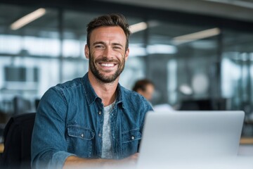 Cheerful middle-aged man wearing glasses working on a laptop in a modern office, representing success, experience, and professionalism.