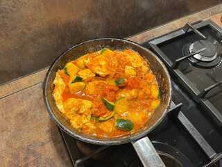 Homemade egg balado cooking in a pan on the stove. Warm comfort meal with vegetables and sauce
