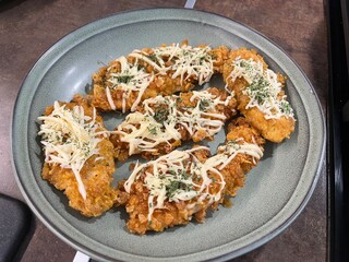 Crispy fried chicken topped with melted cheese and herbs on a gray plate. Comfort food, perfect for restaurant menu or fast food design