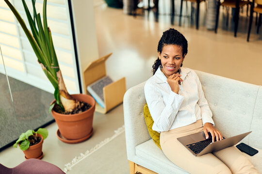African-American Woman Working on Laptop in Modern Office Lounge