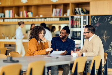 A Woman and African-american Man Collaborate with Caucasian Man in Modern Office Café Discussion