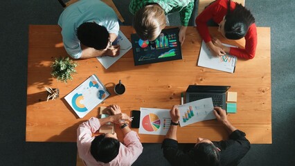 Top down view of business woman explain and present financial chart. Diverse group discuss and listen presentation about stock market statistic at meeting table with investment graph. Convocation.