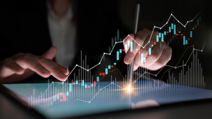 A business professional engages with stock market data on a digital tablet, showcasing glowing...