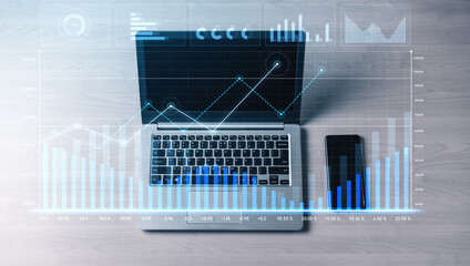 Modern workspace featuring a laptop displaying financial data graphics and a smartphone. Ideal for...
