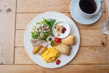 Healthy breakfast plate with scrambled eggs salad and coffee on wooden table