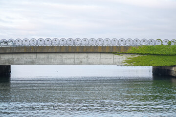 Concrete bridge over calm river with decorative railing and green foliage at Hokkaido, Japan