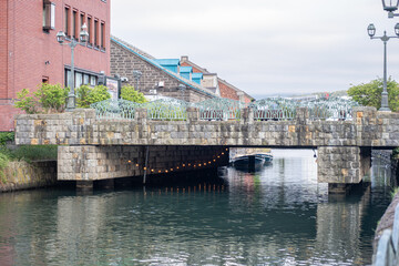 Stone bridge over canal in urban area with buildings and street lamps at Hokkaido, Japan