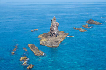 Rock formation rising from clear blue ocean water in coastal seascape at Cape Kamui, Kozakicho, Hokkaido, Japan