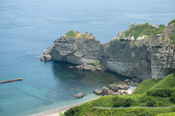 Rocky cliffs overlooking clear ocean water on a sunny day at the coast at Cape Chikyu, Muroran, Hokkaido, Japan