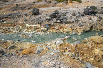 Natural hot spring water flowing through rocky geothermal landscape outdoors at Noboribetsu Jigokudani Valley, Noboribetsu, Hokkaido, Japan