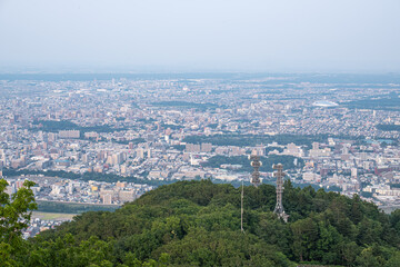 Panoramic view from Moiwa mountain, Cityscape view from green hill with communication towers in urban area at Sapporo, Hokkaido, Japan