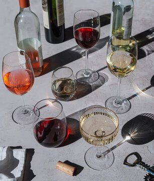 Bottles and glasses of wine with shadows on gray background.