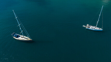 Aerial view of two sailing boats anchored in the middle of the blue sea. Boat holiday concept.