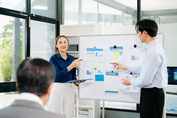 Obraz premium Asian business team presenting charts and reports in modern office meeting, showcasing teamwork, communication, and corporate strategy