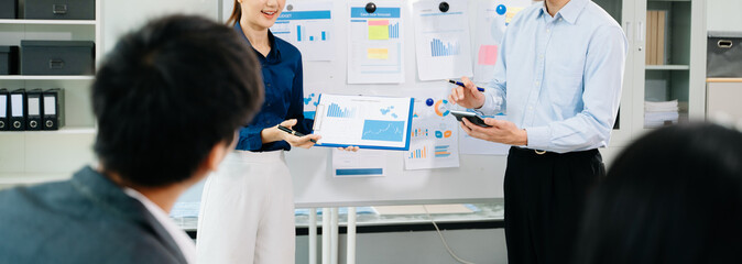 Asian business team presenting charts and reports in modern office meeting, showcasing teamwork, communication, and corporate strategy