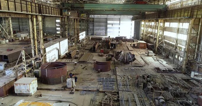 Huge workshop for assembling steel structures and steel bridges. A large shipyard or steel structure factory from the inside. Fabrication of steel structures. Industrial workshop interior. 