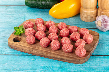 Raw beef meatballs over board