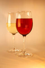 Two elegant wine glasses filled with red and white wine, glowing in golden light—perfect for Christmas dinners, festive brochures, seasonal advertising, or holiday celebration campaigns.