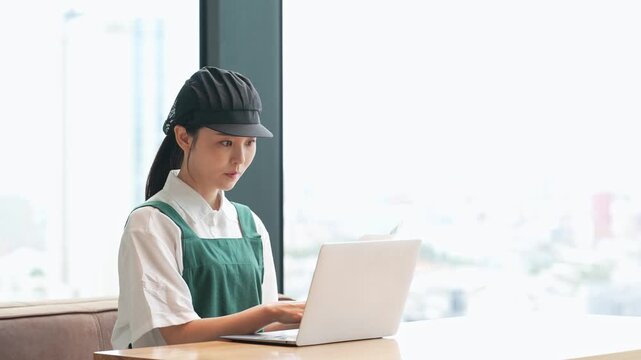 ノートパソコンでデータ入力する飲食店店員