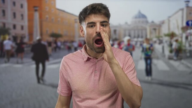 Hispanic man wearing pink shirt opens mouth and clenches fists beside building; triumph excitement.