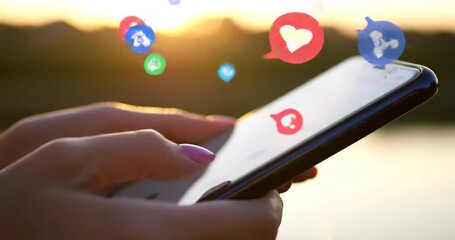 hands holding a smartphone with social media icons floating above it. - Powered by Adobe