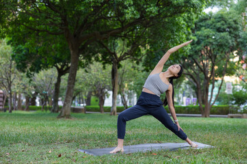 Fototapeta premium Woman practicing reverse warrior two yoga pose outdoors