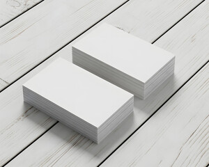Two thick stacks of blank white business cards displayed on a light wood surface for mockup purposes