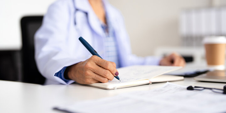 Doctor writing on a notepad in medical office.