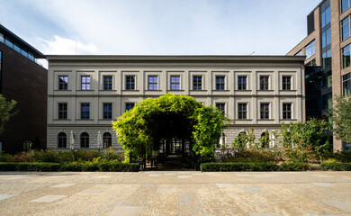 Modernly renovated old building in the city center with lots of bushes and greenery in front of the entrance. Classic house in the middle of a modern business center.