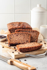 Chocolate zucchini bread cake sliced. Moist chocolate cake with grated zucchini, cocoa powder and chocolate chips on white tile kitchen background