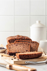 Chocolate zucchini bread cake sliced. Moist chocolate cake with grated zucchini, cocoa and chocolate chips on white tile kitchen background with copy space