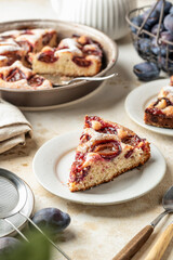 Homemade The New York Times plum cake. Slice of autumn fruit pie in a plate on beige textured background. Home cooking, recipe