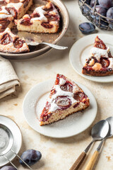 Homemade The New York Times plum cake. Slice of autumn fruit pie in a plate on beige textured background. Home cooking, recipe