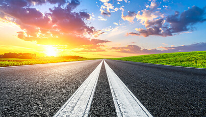 Fototapeta premium White arrow on the asphalt road during the sunset. Straight ahead way concept, path to success direction, business career future guidance, journey to the destination