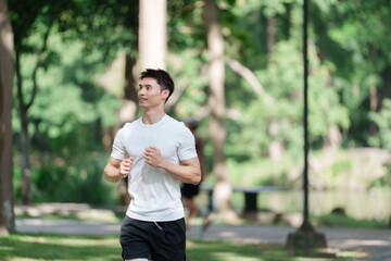 Young man jogging outdoors in lush green park