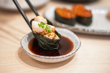 Sushi in chopsticks dipping with soy sauce