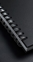 Black spiral notebook detail, metal rings gleam on dark background