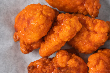 Crispy boneless buffalo wings coated in a bright orange spicy sauce.