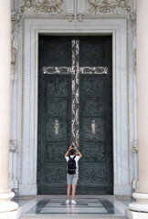 Tourist taking a photo of the monumental bronze Holy Door of the Basilica of Saint Paul Outside the Walls in Rome, Italy. Religious architecture, travel and culture scene under soft daylight.