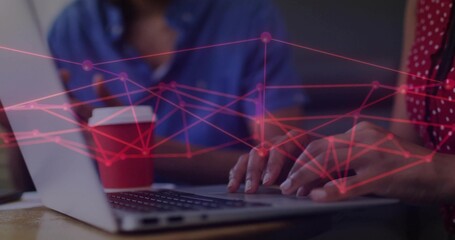 Collaborating colleagues typing on laptop in office, with red coffee cup and network overlay