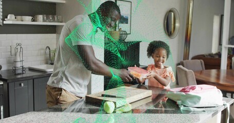Father and daughter handing clear plastic food container in home kitchen, with green apple