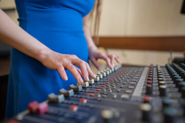 Hands Adjusting Sound Levels on Mixing Console. 