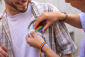 Partner pinning rainbow badge on man's shirt