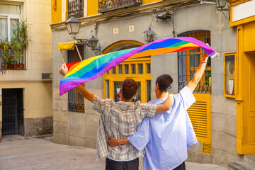 Couple celebrating diversity holding rainbow flag in city
