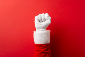 A white gloved fist raised against a bold red background, dressed in a Santa sleeve with white fur, conveying festive spirit, celebration, joy, and holiday cheer for Christmas and New Year themes